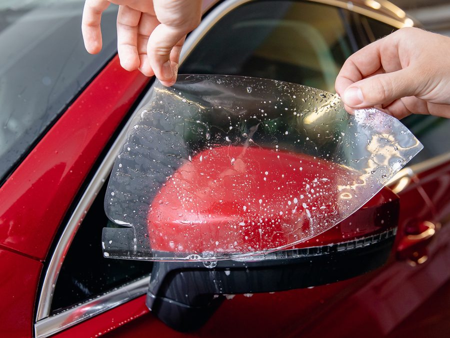 Master man installs vinyl film in risk zone of windshield to protect car body paint.